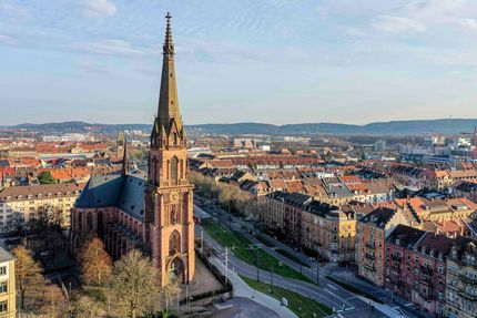 Eine Luftaufnahme einer großen Kirche mit einem Kirchturm mitten in einer Stadt.