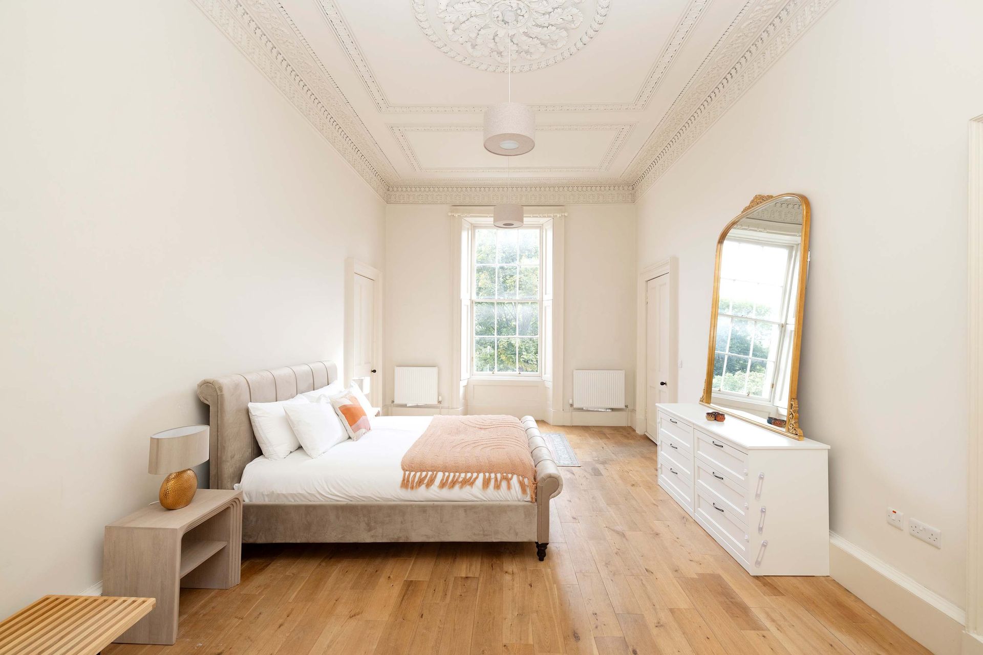 A bedroom with a bed , dresser , nightstand and mirror.