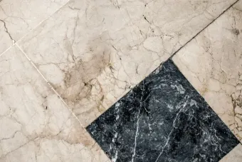 Baldosas negras diagonales con un patrón de suelo de mármol beige.