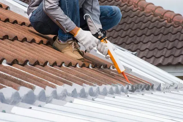Un trabajador corta con una sierra los paneles del tejado de una casa.