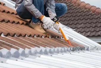 Un trabajador corta con una sierra los paneles del tejado de una casa.