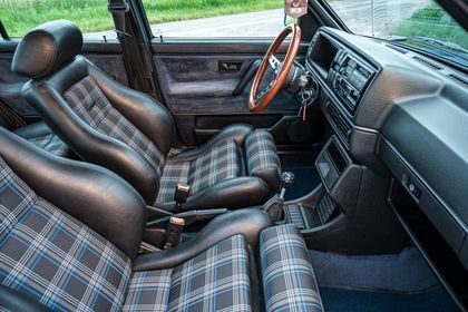 El interior de un coche con asientos a cuadros y un volante de madera.