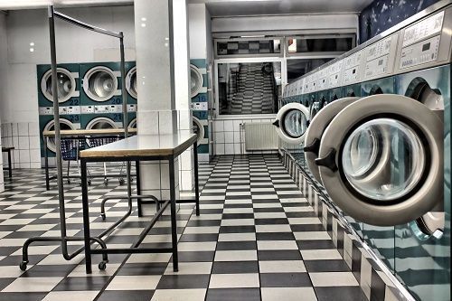 Una lavandería con suelo cuadriculado y filas de lavadoras.