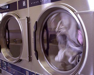 Una lavadora y secadora en una lavandería con ropa lavándose