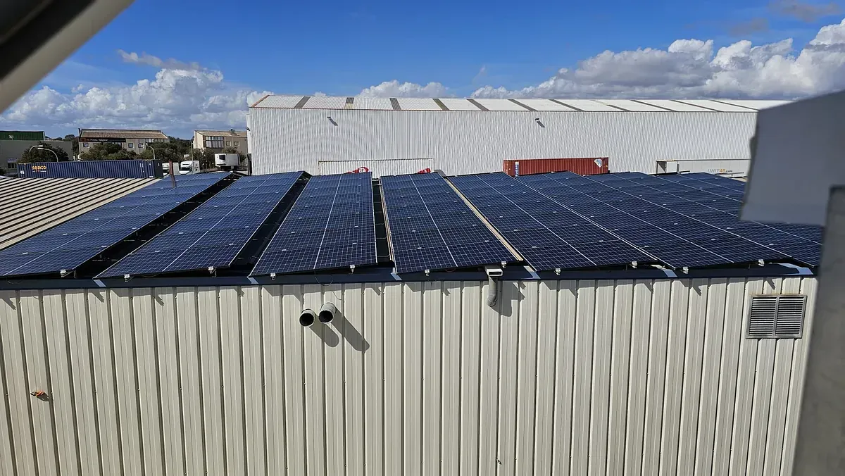 Un edificio blanco con muchos paneles solares en el techo.