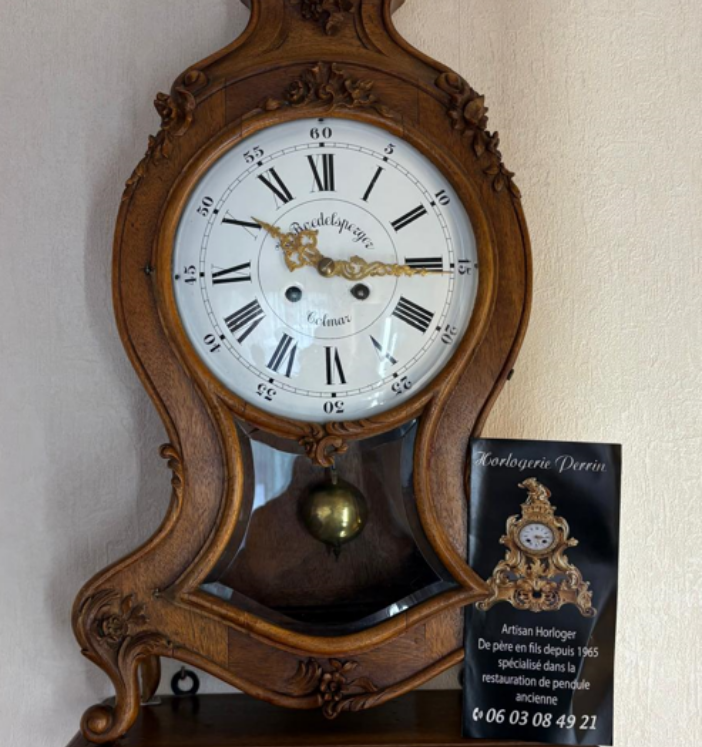 Horloge ancienne en bois avec cadran blanc, chiffres romains et pendule.