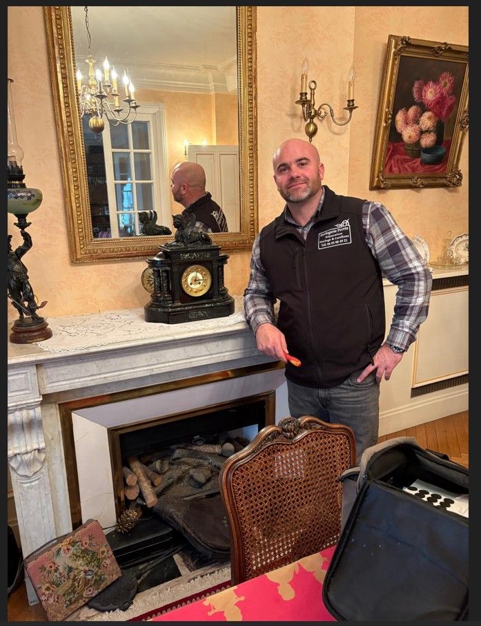 Un homme se tient près d'une cheminée, où repose une horloge.