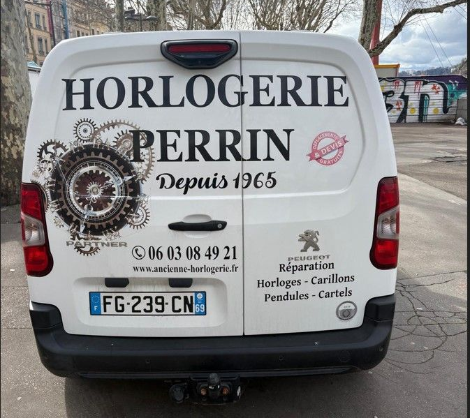 Fourgonnette Peugeot blanche avec le logo Horlogerie Perrin.
