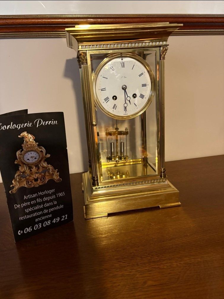 Horloge ancienne dorée à pendule apparent et boîtier en verre.