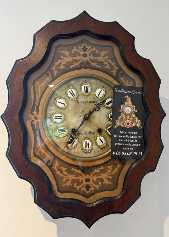 Horloge ancienne avec cadre en bois décoratif et cadran orné.