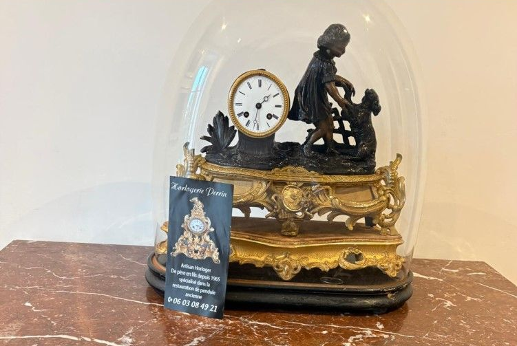 Horloge ancienne sous cloche en verre avec figurine d'enfant et de chien.