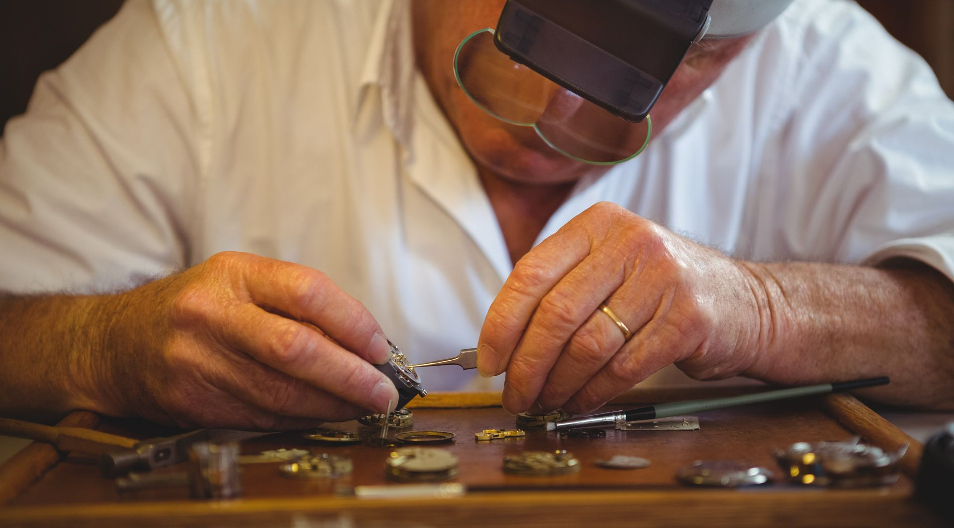 Un horloger répare une petite horloge dans son atelier.