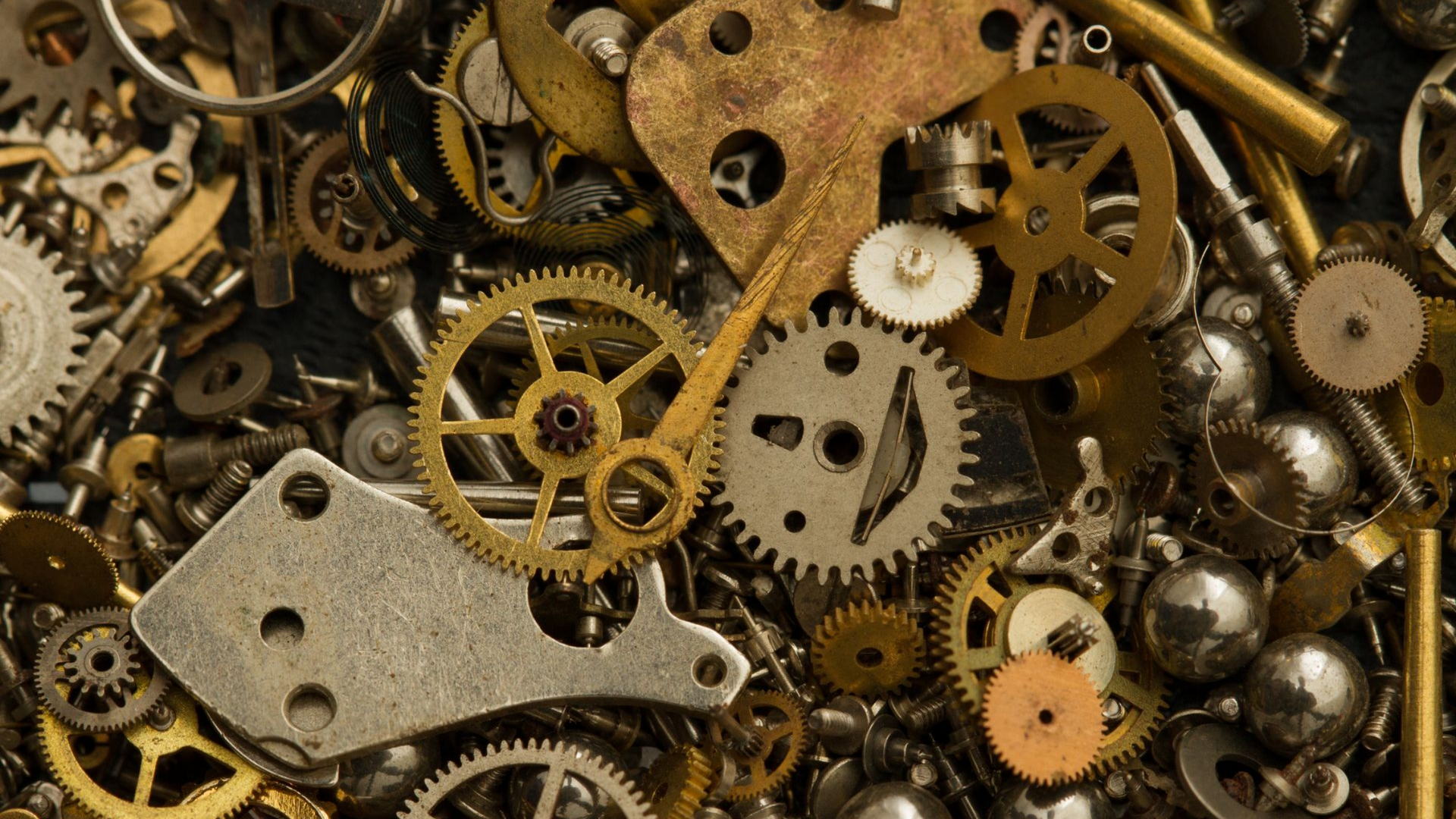 Gros plan de diverses pièces de montres en or et en argent, notamment des engrenages, des ressorts et des vis.
