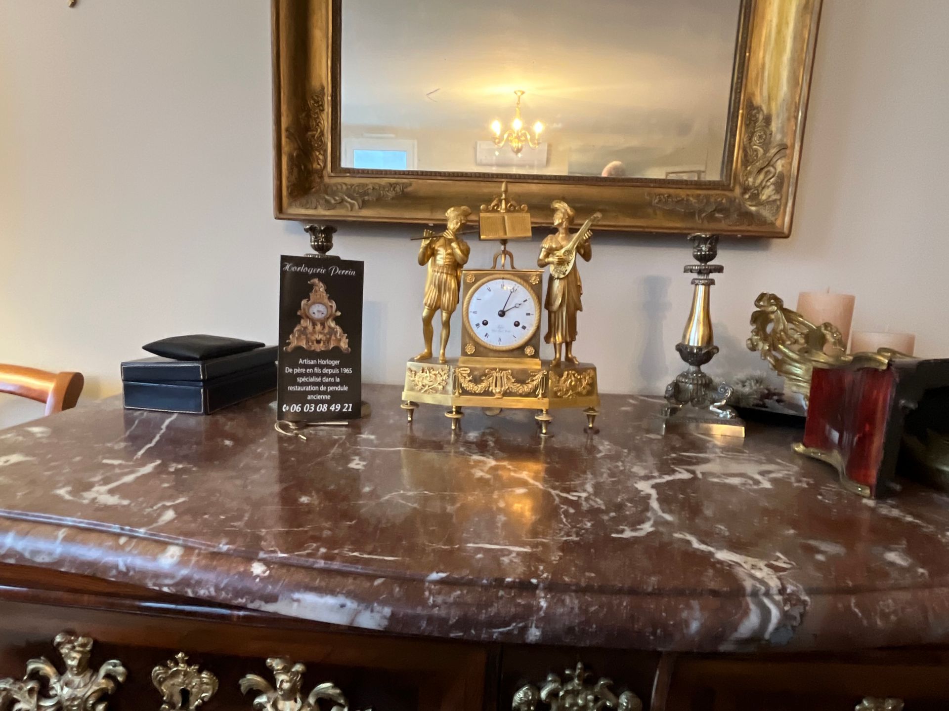 Une horloge élégante avec une sculpture dorée.