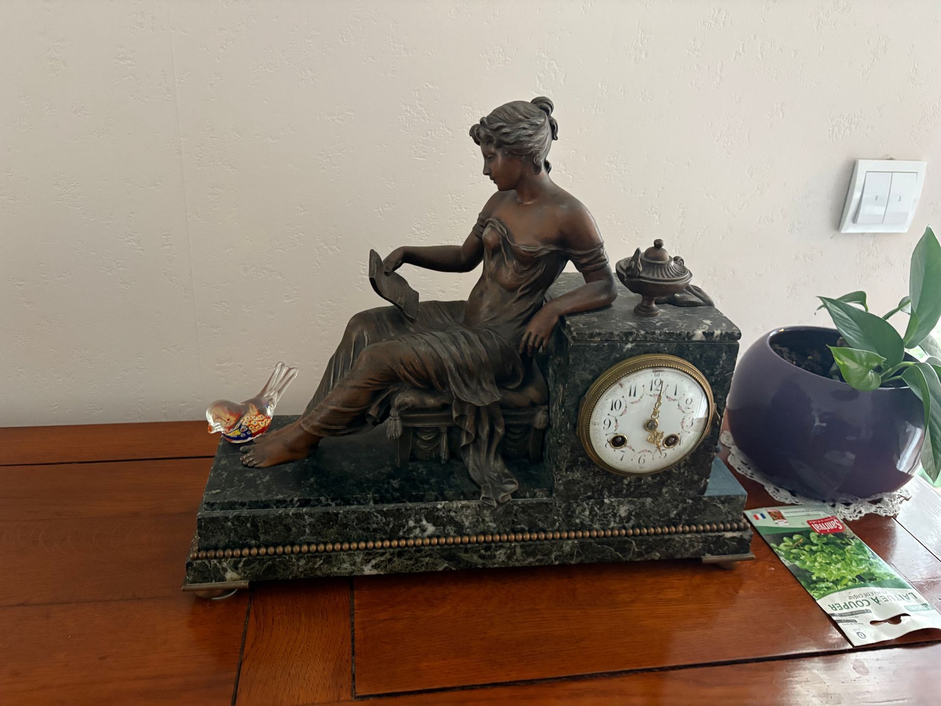 Une horloge en marbre avec une sculpture de femme en bronze.