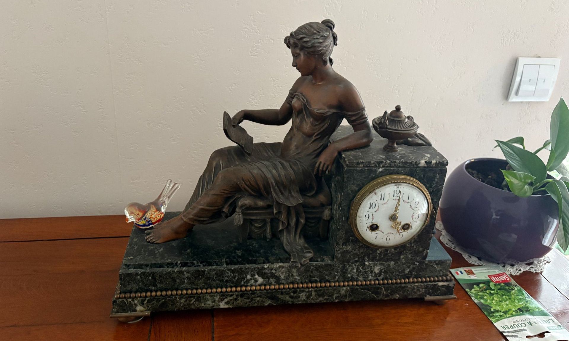 Une horloge repose sur un socle en marbre décoré.
