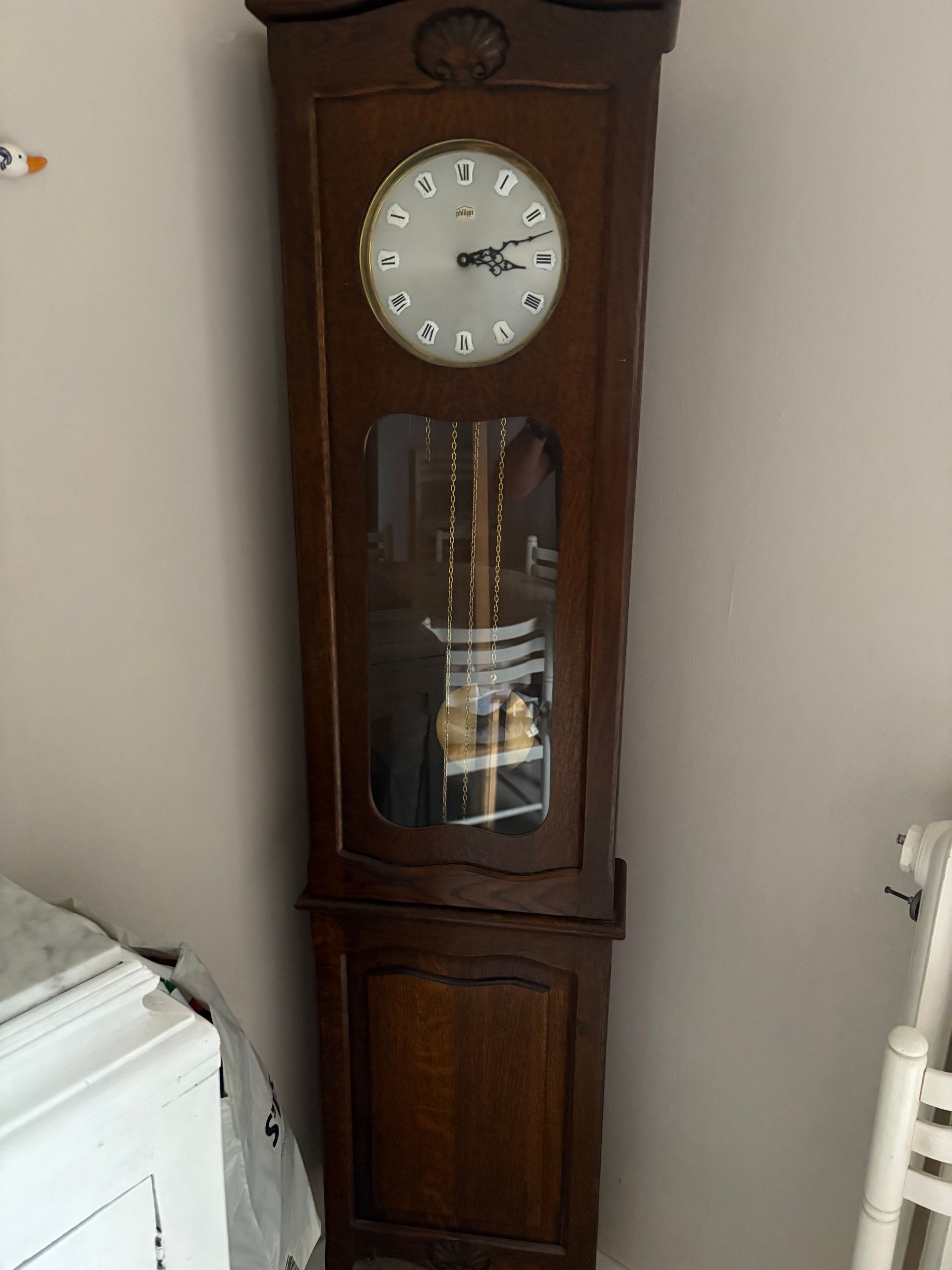 Une grande pendule en bois, réparée par un professionnel.