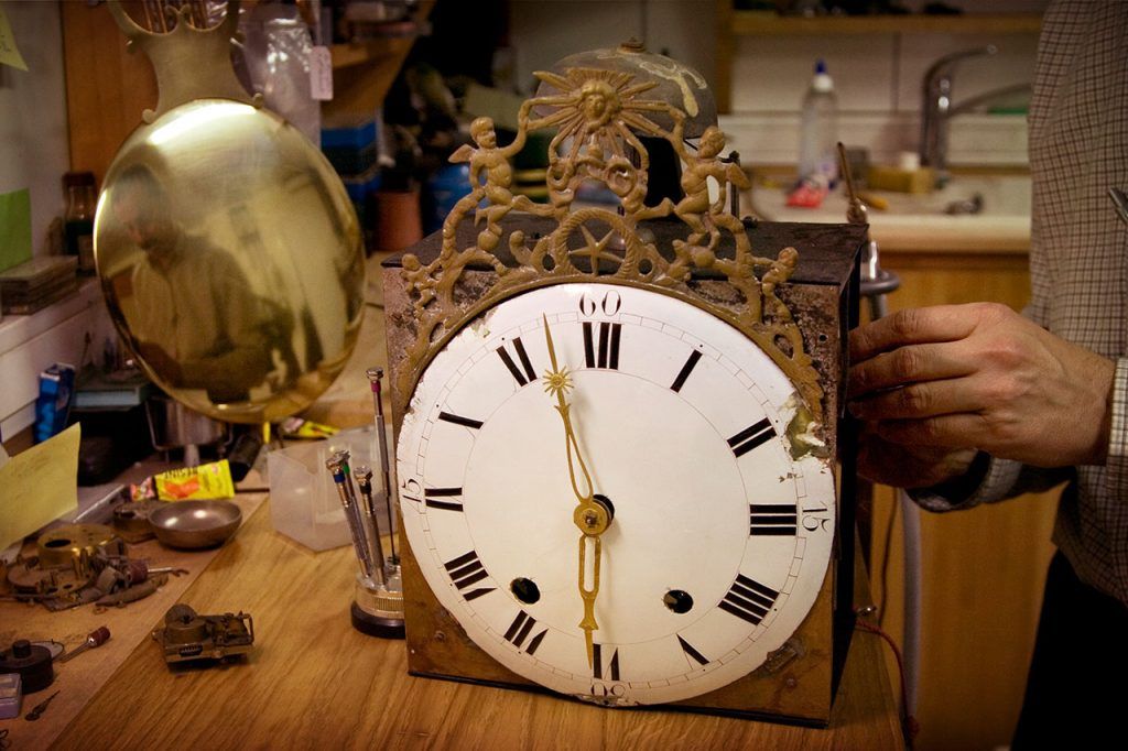 Un artisan travaille minutieusement sur une horloge ancienne.