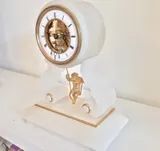 Une petite pendule blanche avec des éléments dorés.