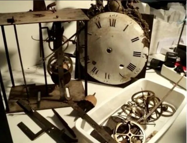 Un mécanisme d’horloge est posé à côté d’outils.