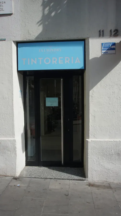 Un escaparate con un cartel azul que dice tintorería
