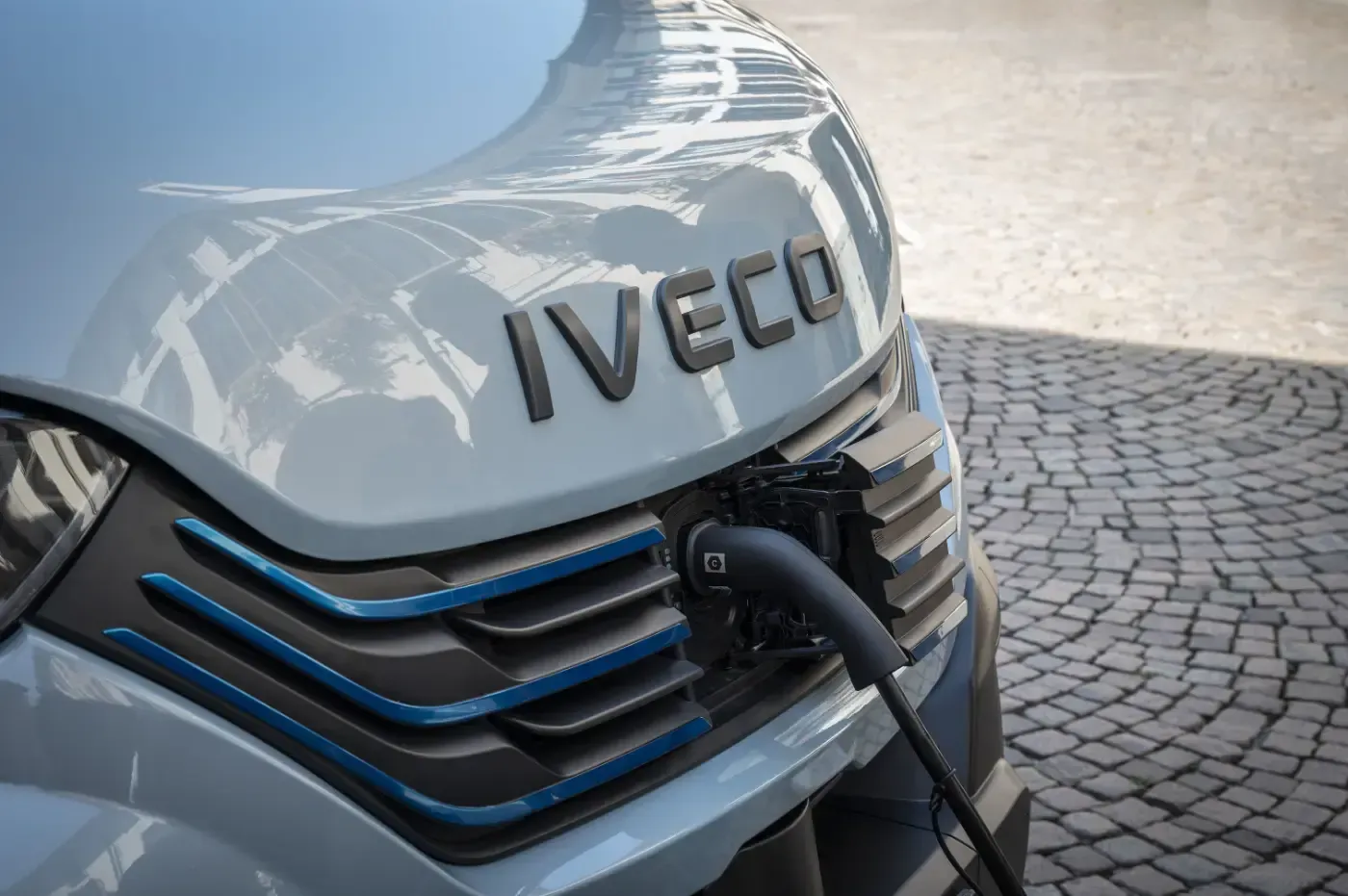 Nahaufnahme eines Iveco-Elektro-Lkw, der an einem gepflasterten Uferabschnitt aufgeladen wird