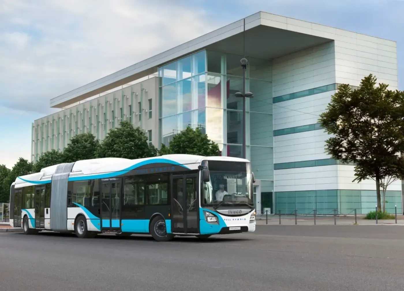 Ein blau-weißer Stadtbus parkt vor einem modernen Glasgebäude.