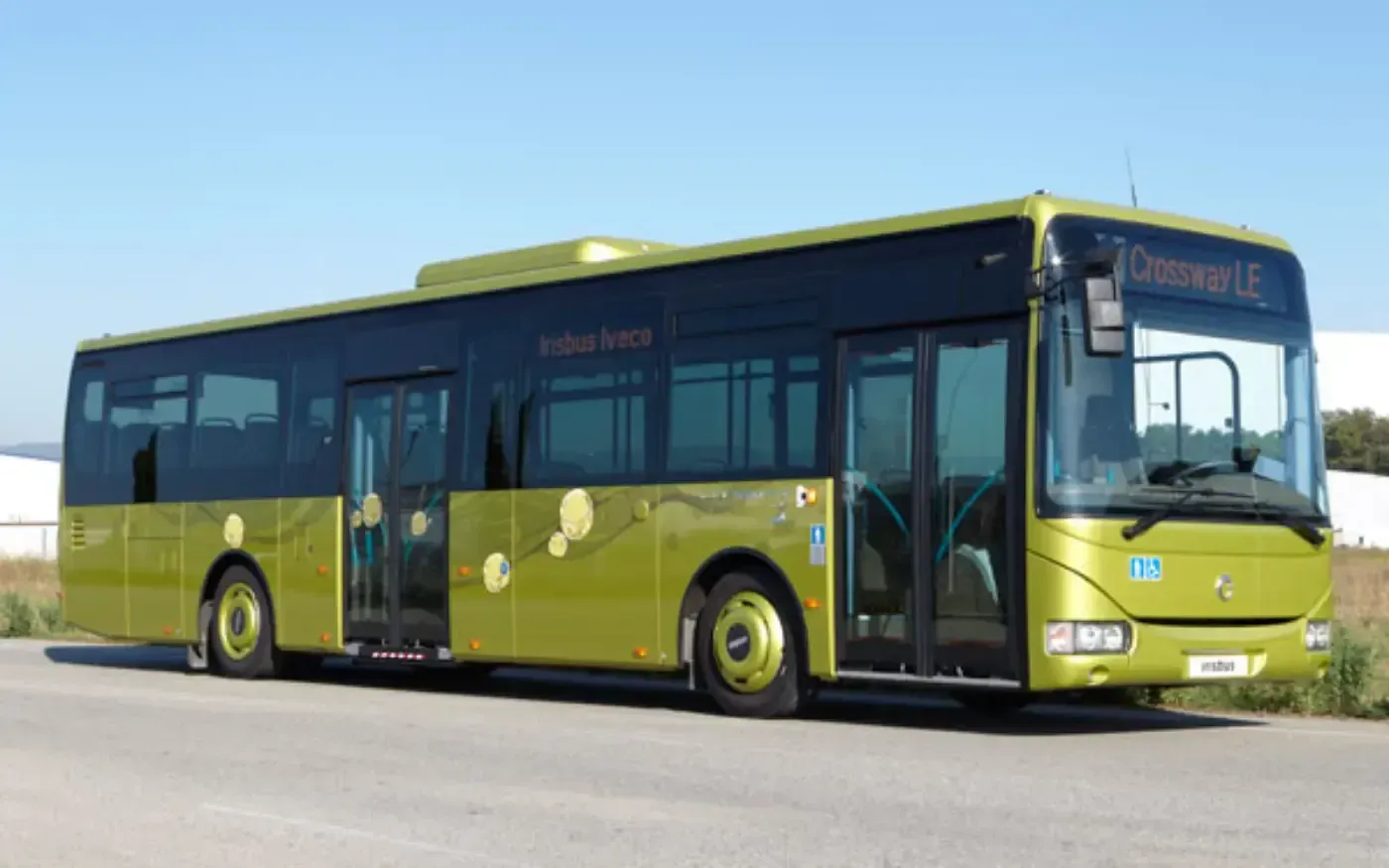 Ein grüner Stadtbus parkt im Freien unter klarem Himmel.
