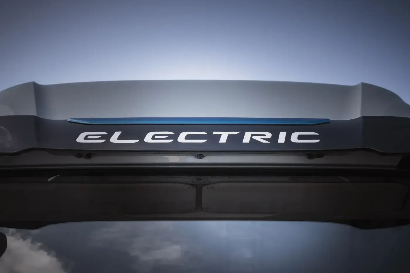 Nahaufnahme eines schwarzen Dachspoilers eines Elektrofahrzeugs mit dem weißen Schriftzug „ELECTRIC“.