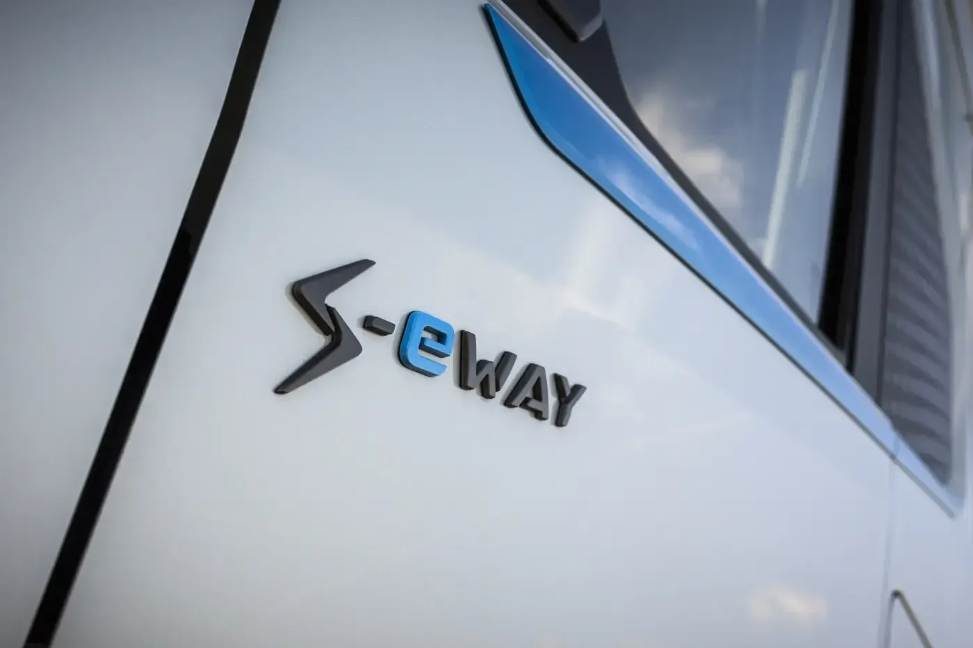 Nahaufnahme eines eWay-Logos auf einer weißen Fahrzeugverkleidung mit einem Fenster darüber