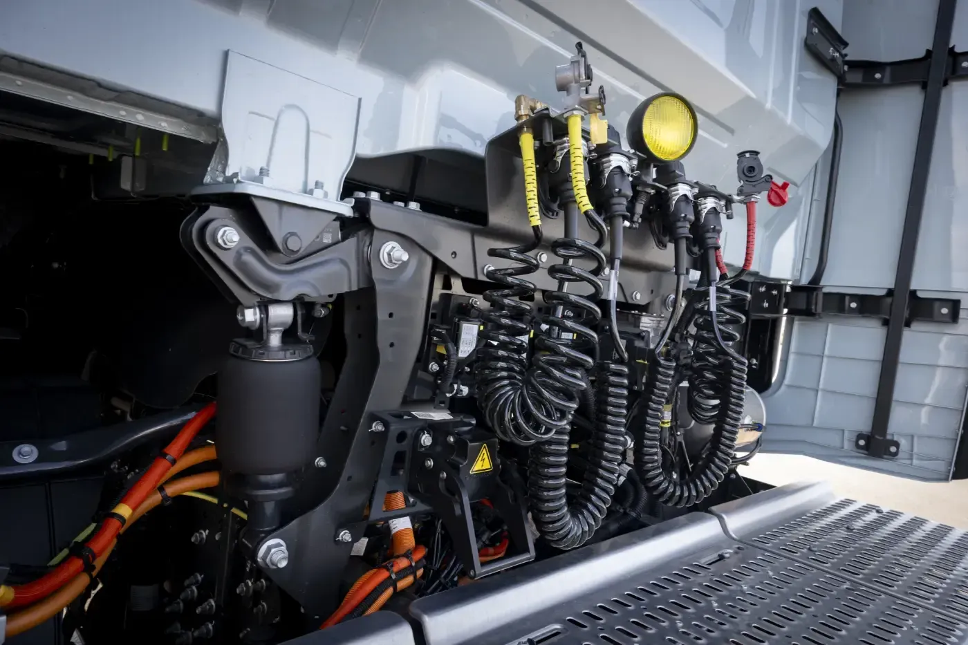 Detaillierter Motorraum mit aufgerollten schwarzen Schläuchen, gelben Lichtern und montierten Maschinen in einem LKW- oder Anhängerfach
