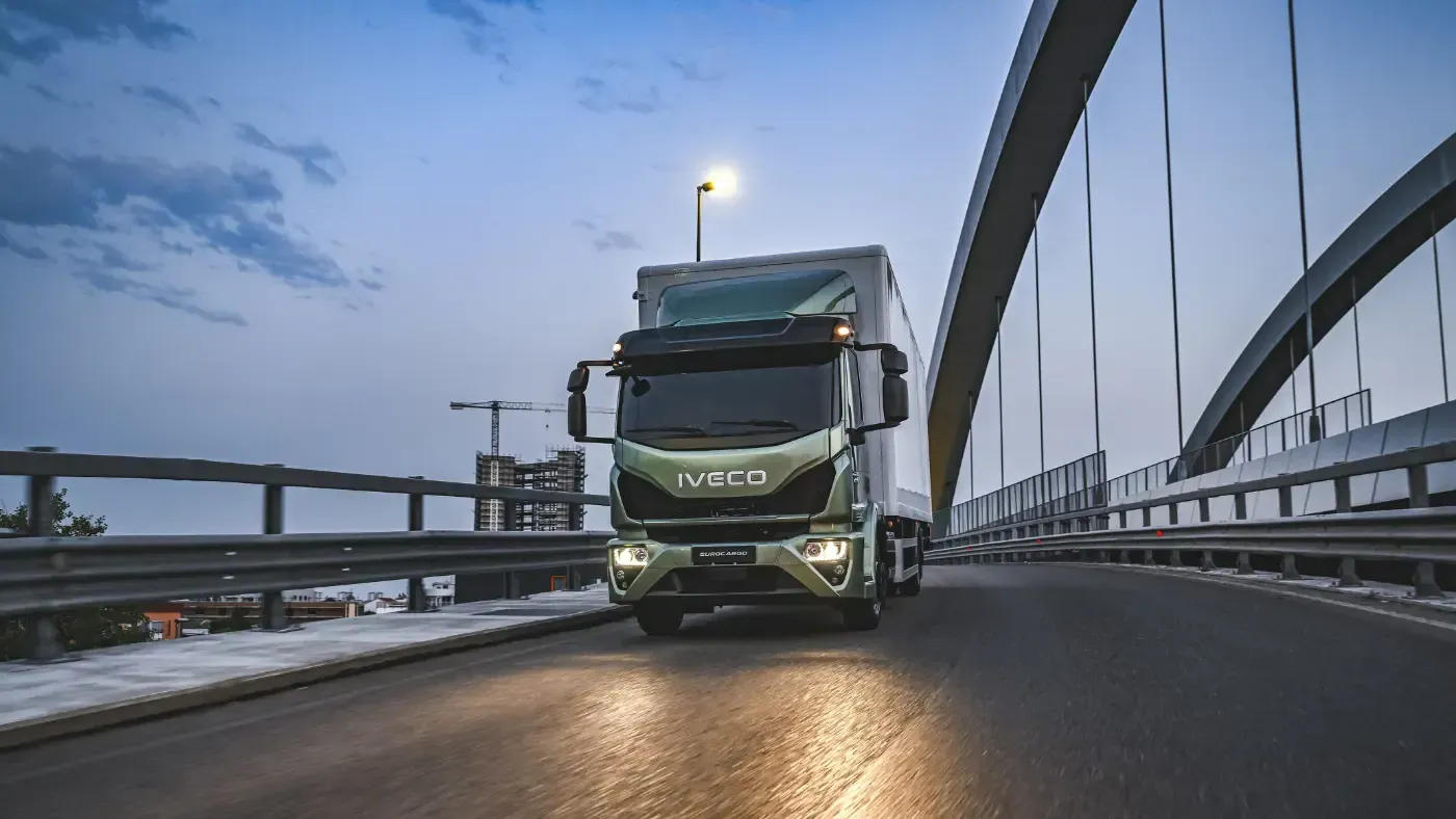 Grüner Volvo-Lkw fährt in der Abenddämmerung über eine Brücke