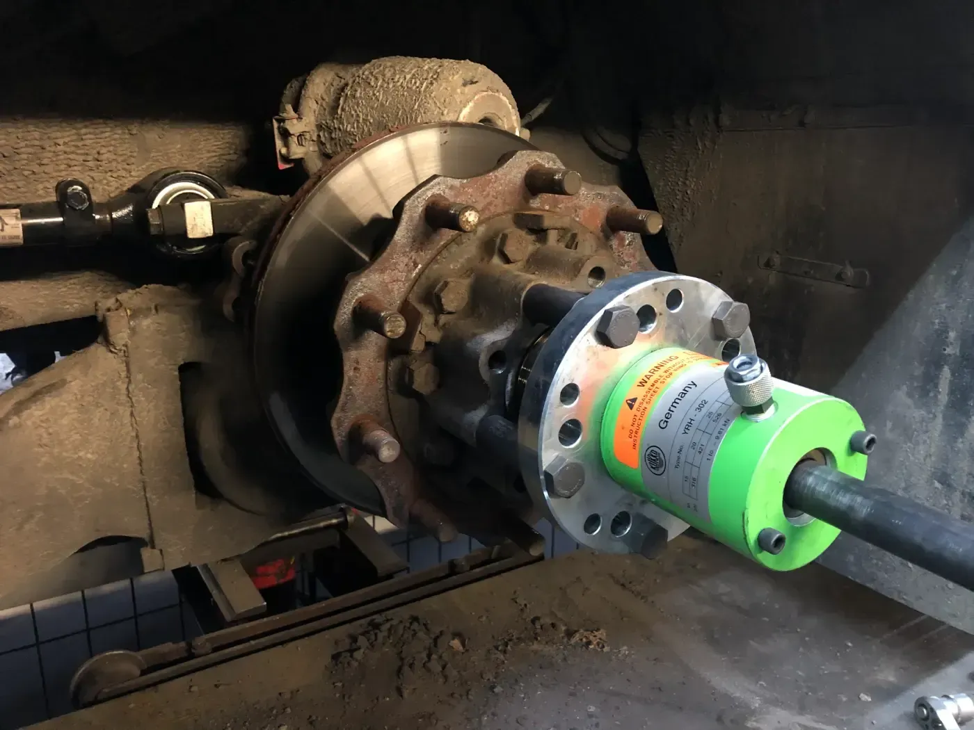 Industriekupplung, die mit einer Maschinenwelle verbunden ist, mit einem hellgrünen und silbernen Stecker an einer rostigen Metallkonstruktion