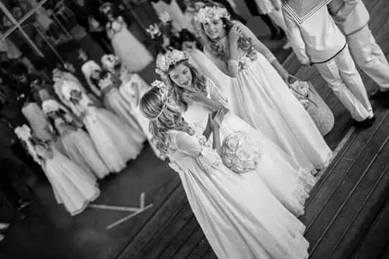 Damas de honor con vestidos blancos posando juntas en una escalera en un evento formal.