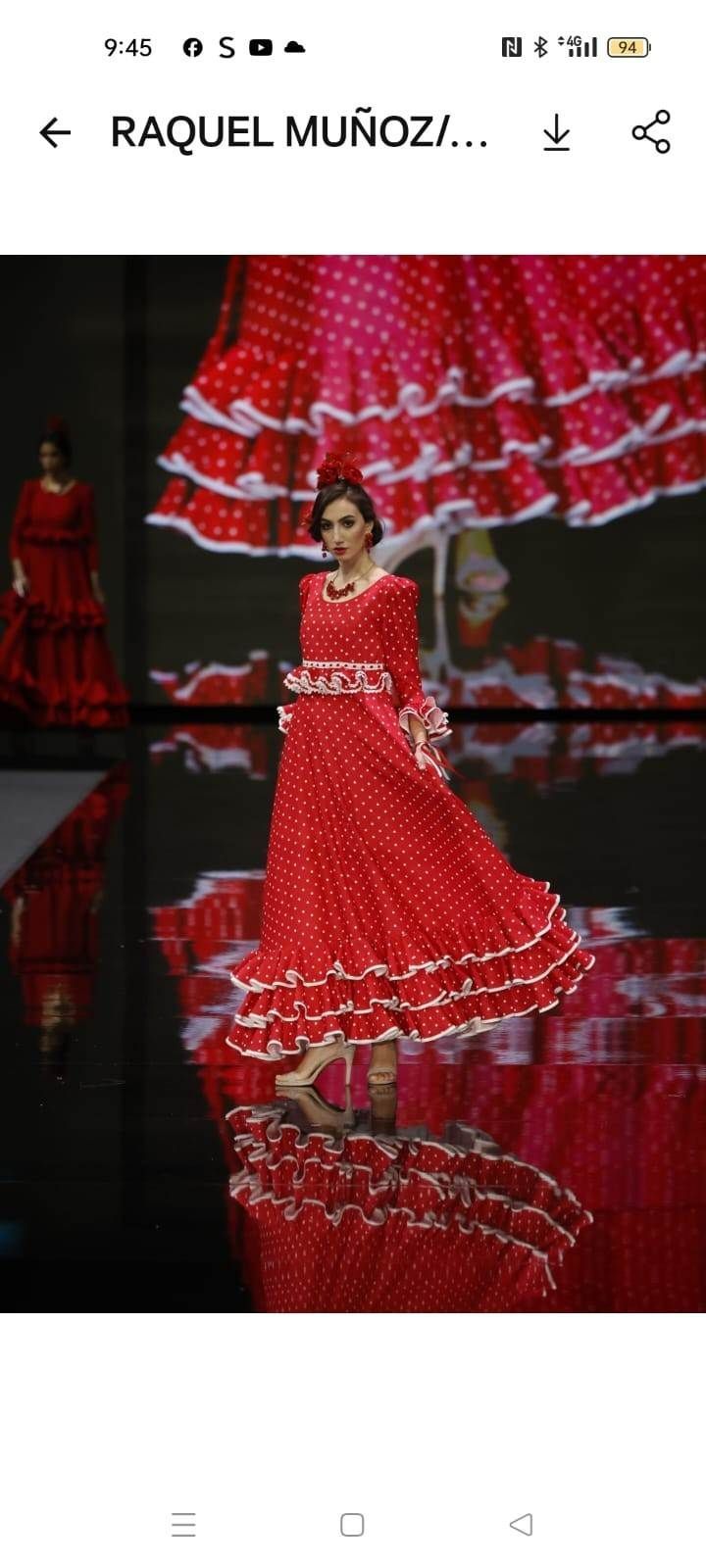 Mujer con un vestido rojo con volantes posando en un escenario con un telón de fondo rojo y blanco a juego.