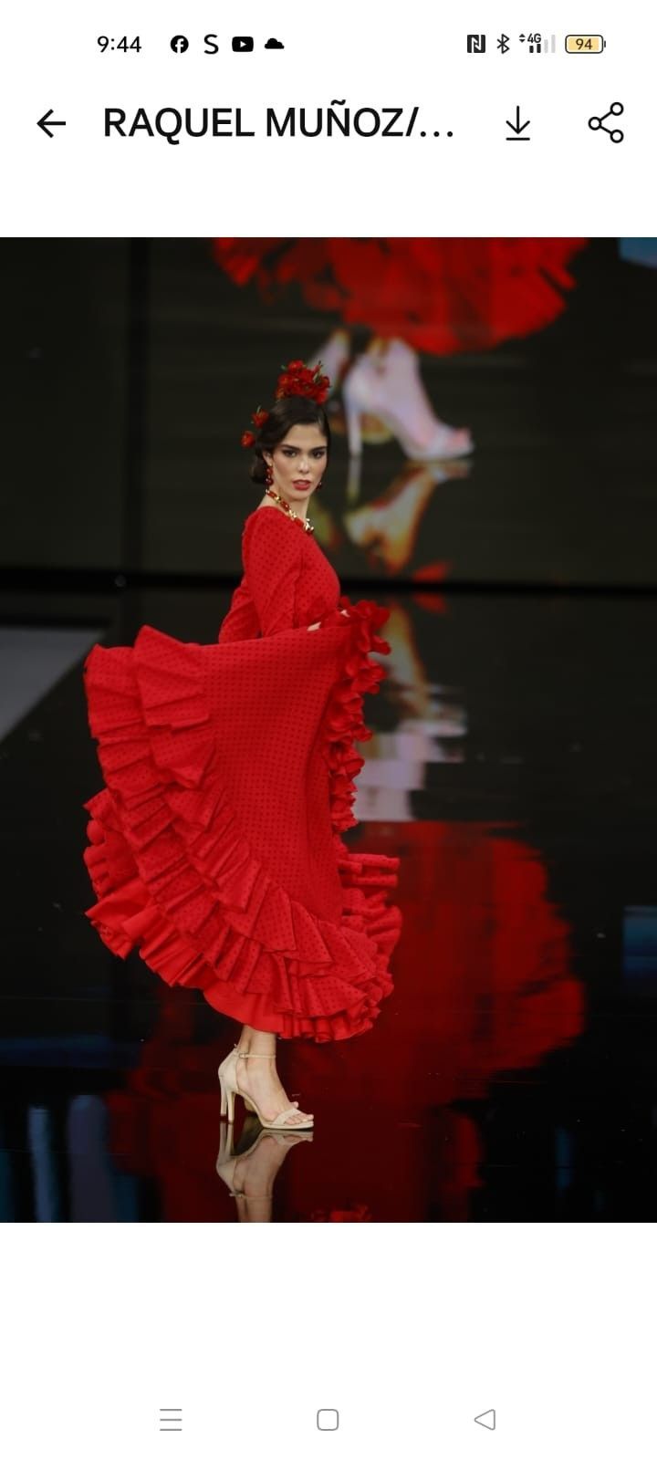 Modelo con un vaporoso vestido rojo con volantes posando en una pasarela.