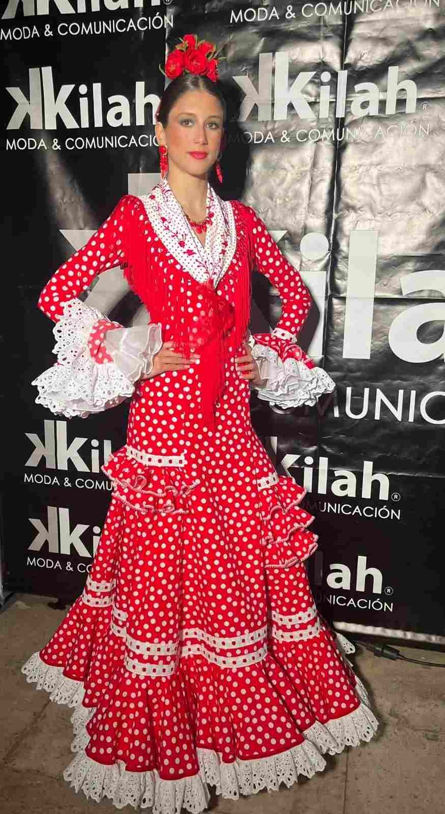 Mujer con un vestido rojo de lunares posando frente a un fondo para un evento de Kilah
