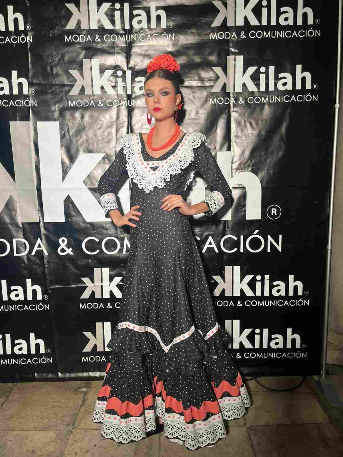 Mujer con un vestido flamenco negro y rojo posando frente a un fondo de moda Kilah.
