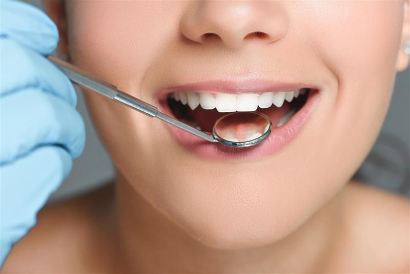 Una mujer está siendo examinada por un dentista.