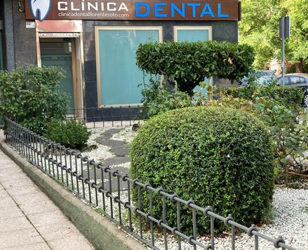Un cartel de clínica dental está encima de una valla.