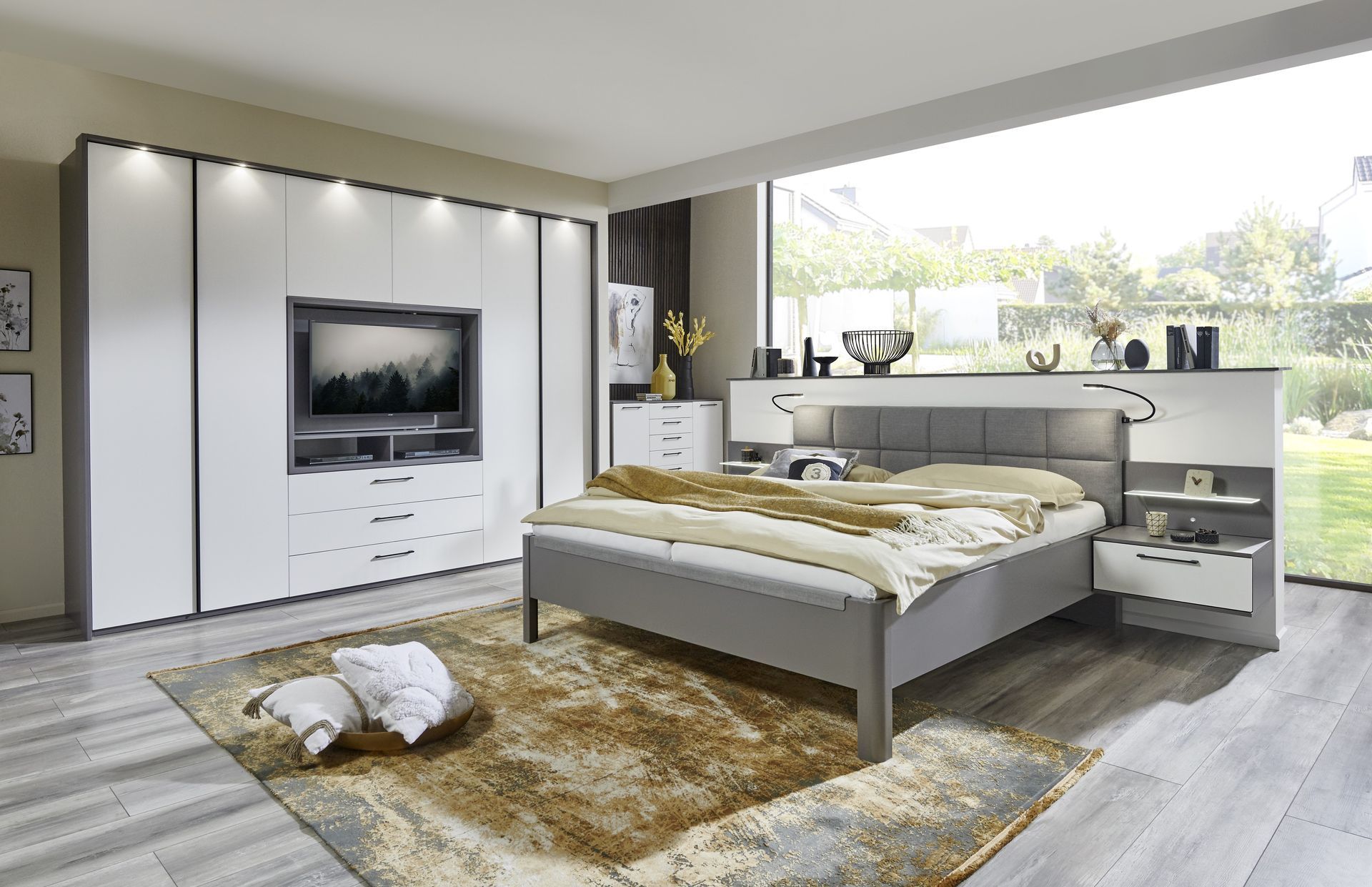 Graues Doppelbett mit weißer Schrankwand daneben