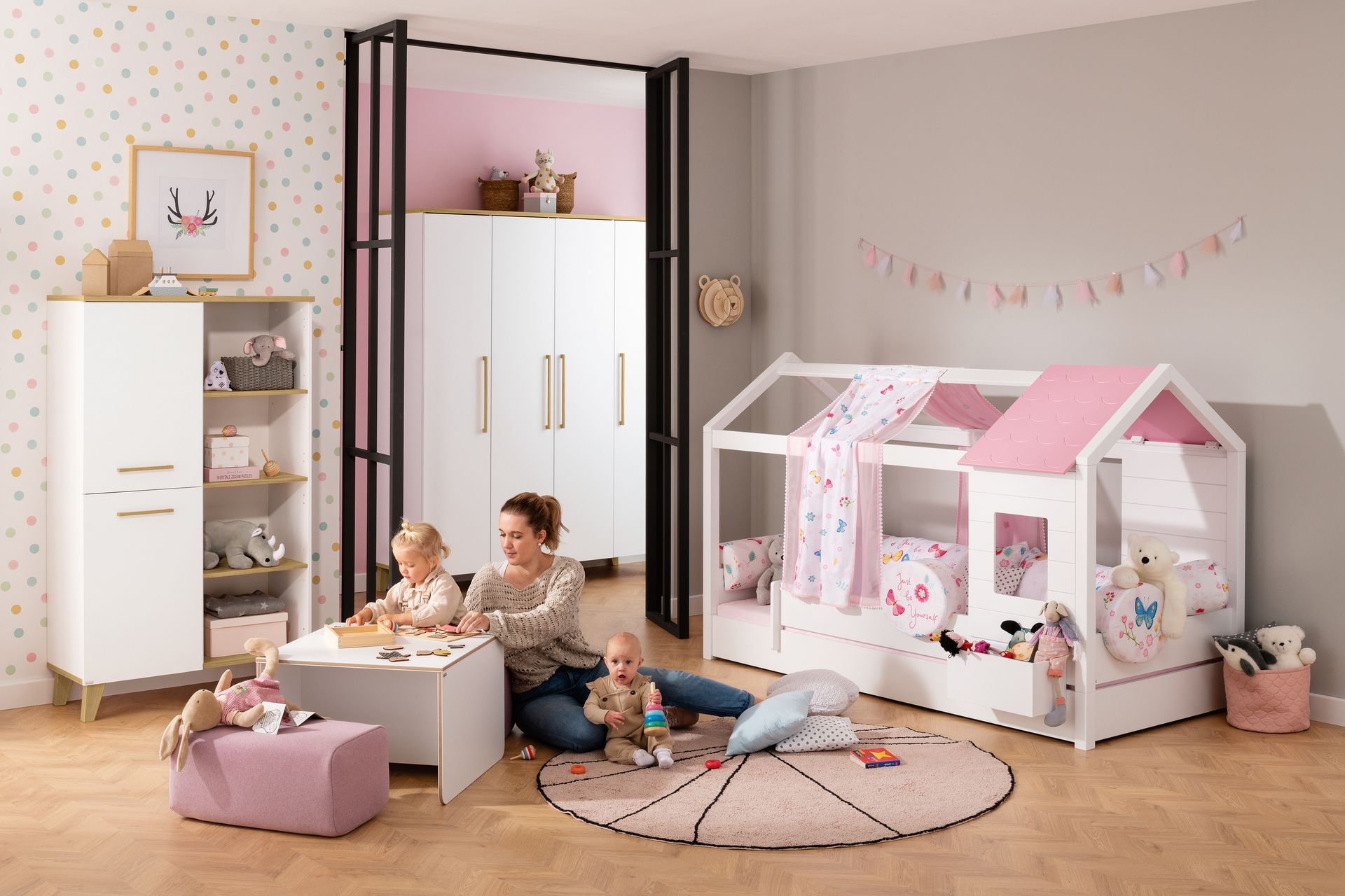 Mutter spielt mit ihren beiden Kindern im pinken Kinderzimmer