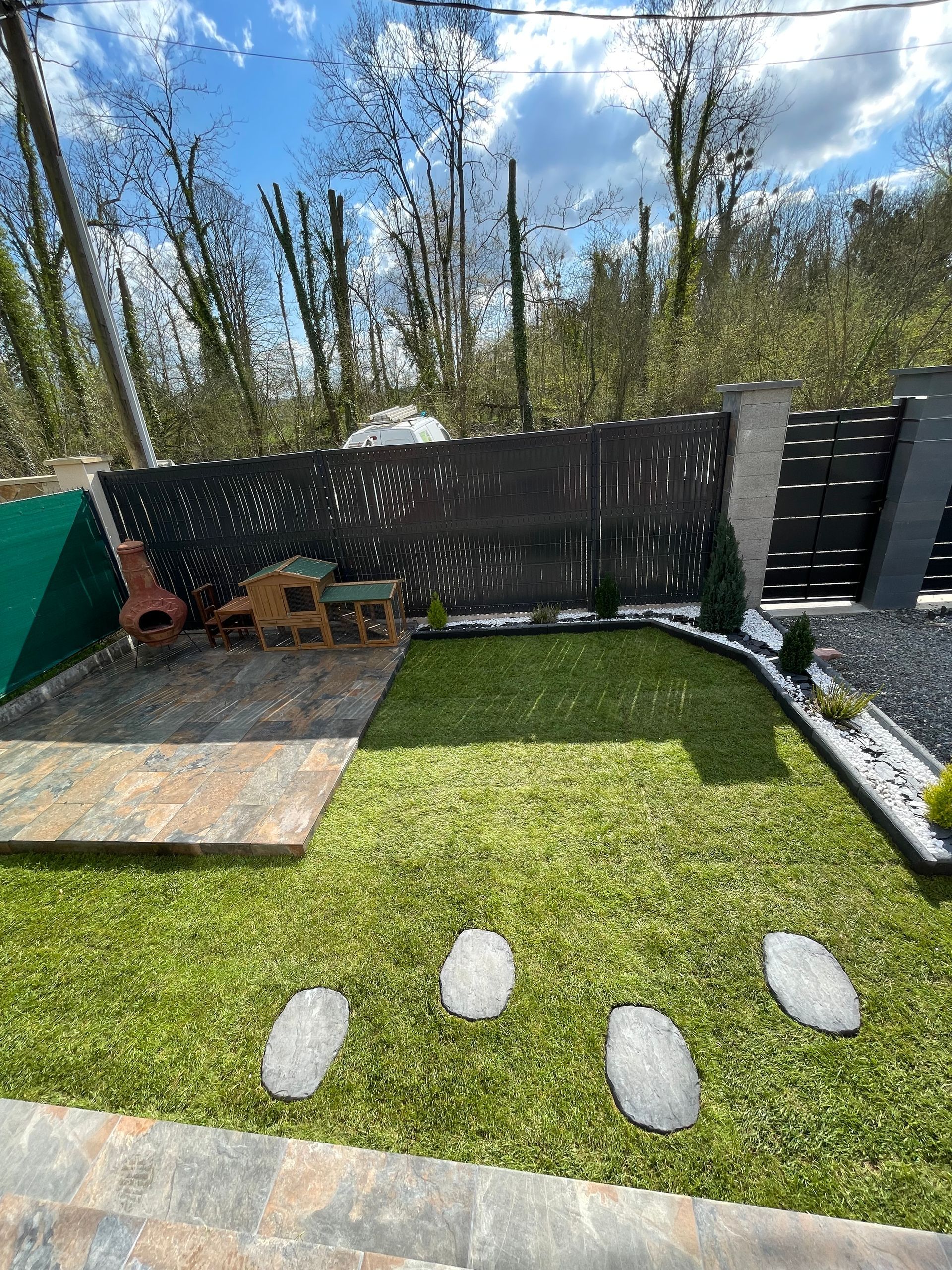 Création paysagère finalisée, comprenant une terrasse en dalle, la plantation de sapin et pose de pelouse