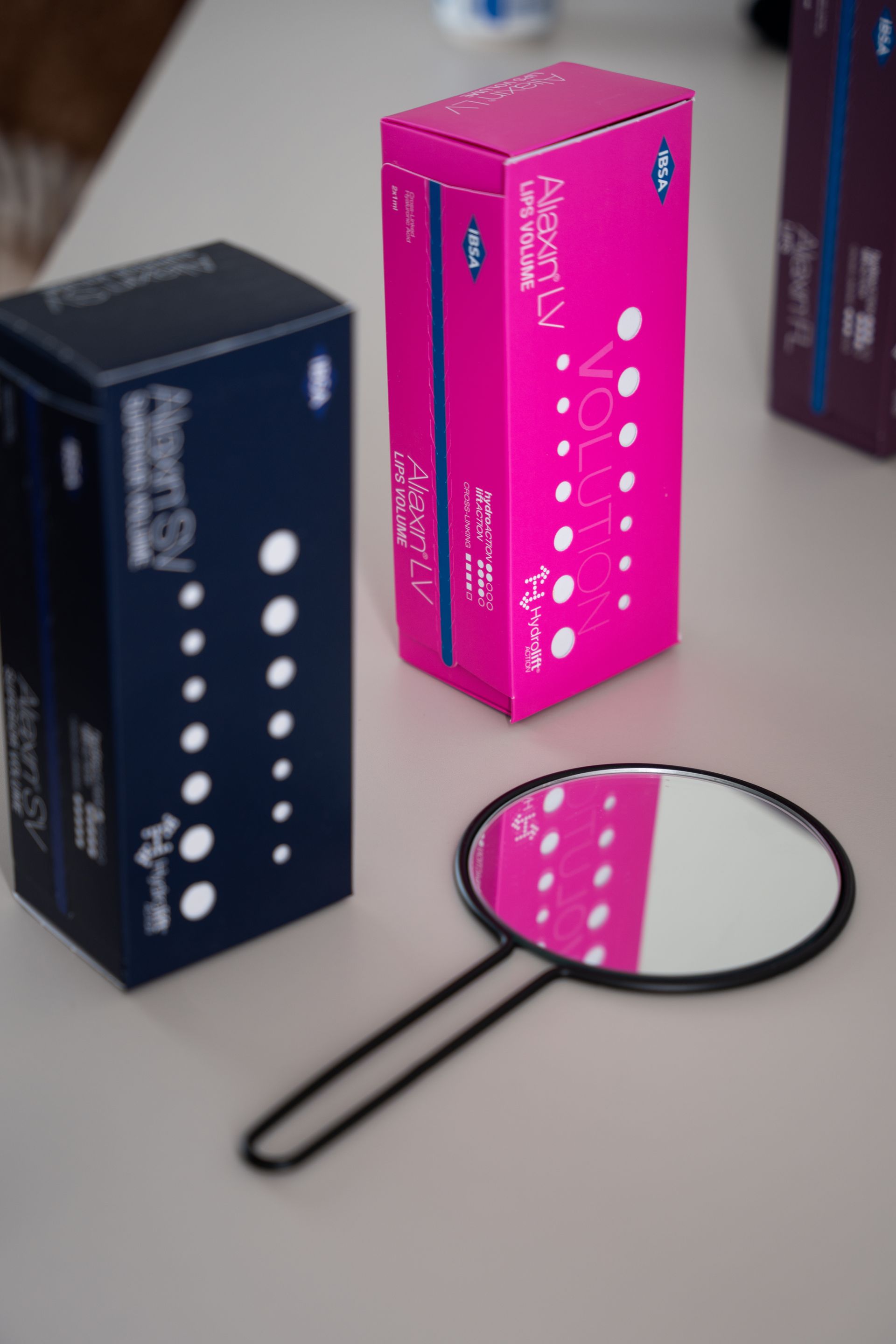 A mirror is sitting on a table next to Aliaxin packages.