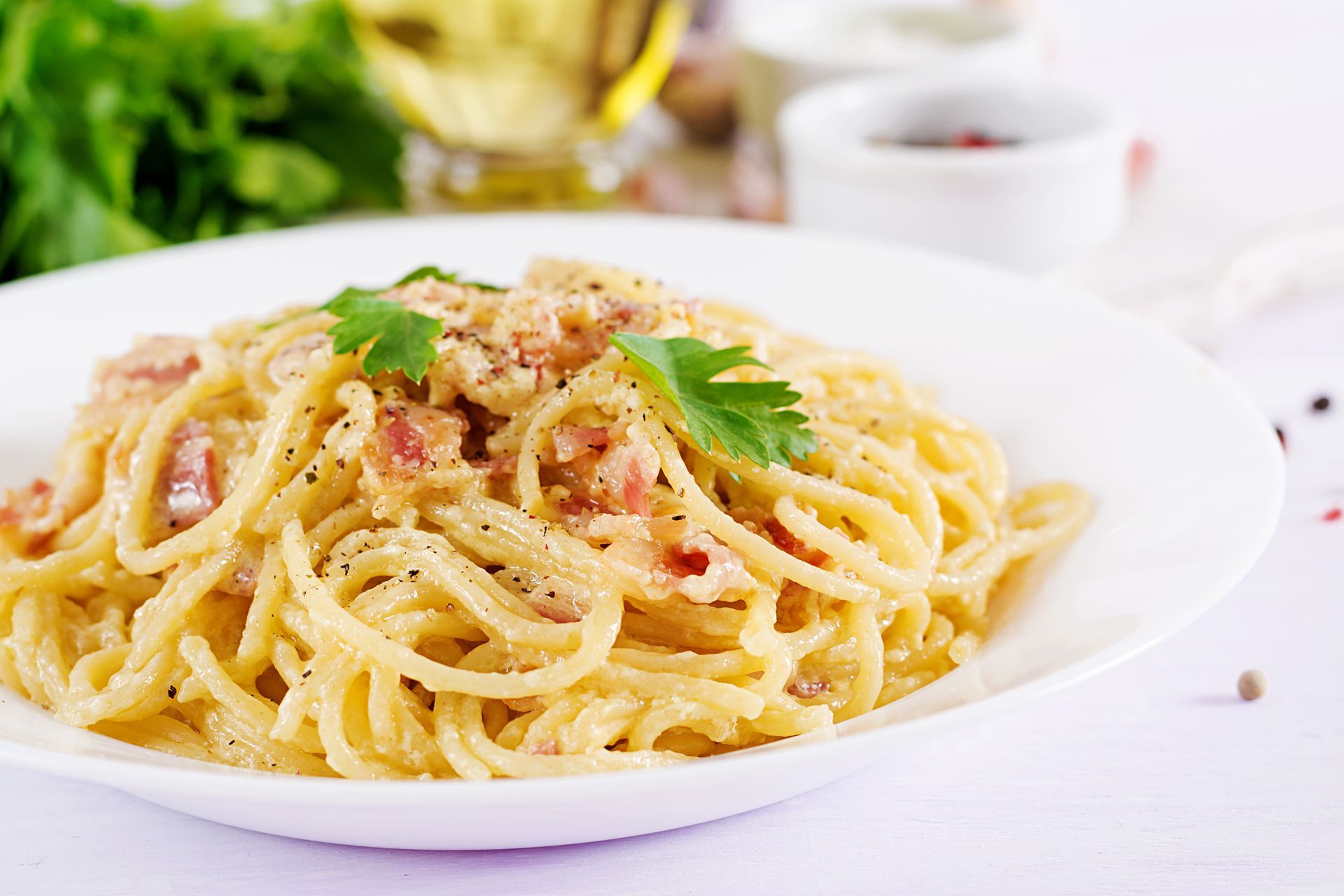 Spaghetti à la carbonara garni de persil sur une assiette blanche