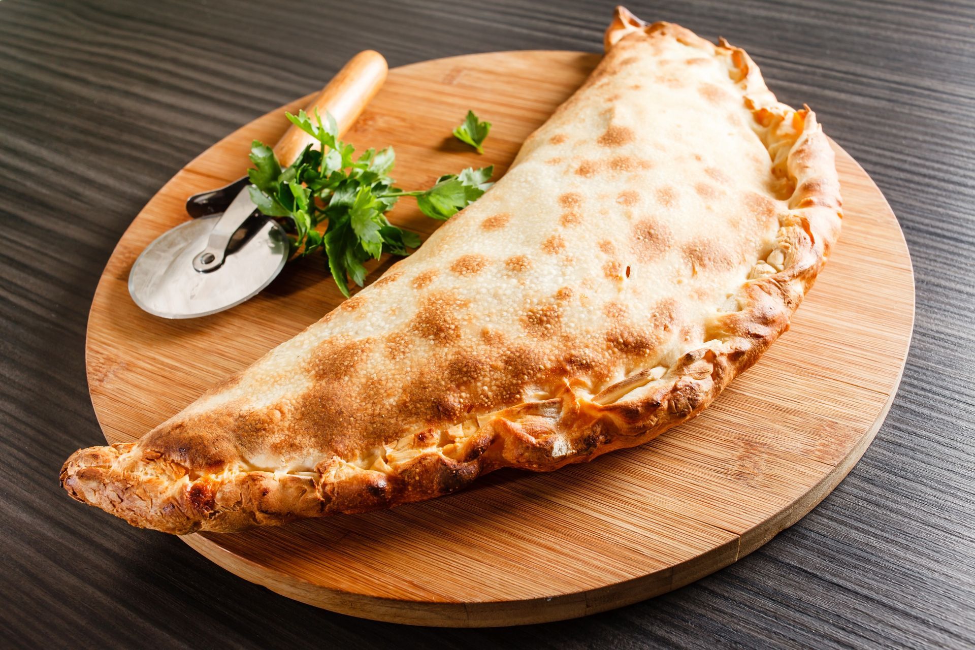 Pizza calzone sur un présentoir en bois avec rouleau à pizza