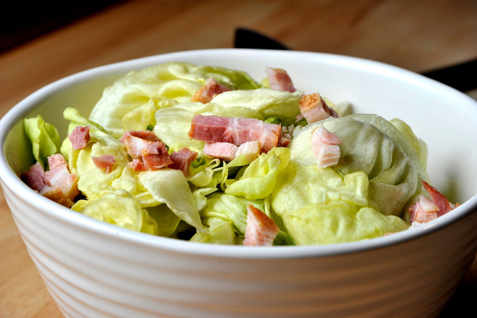 Salade composée dans un bol, garnie de bacon en dés et de sauce crémeuse