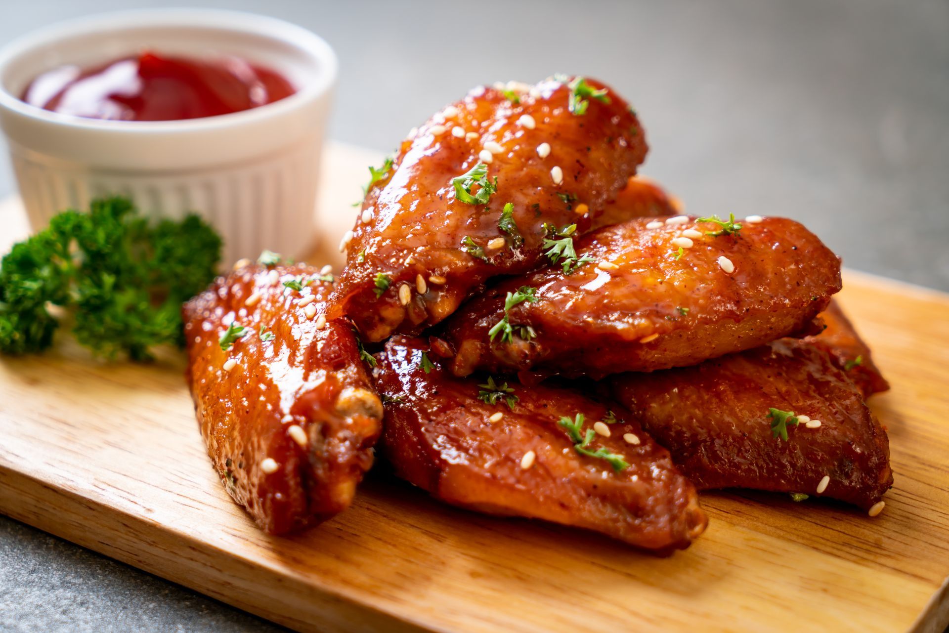 Ailes de poulet sur une planche en bois avec sauce et garniture de persil