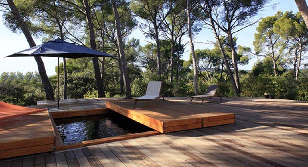 Piscine naturelle avec une terrasse en bois et un salon de jardin