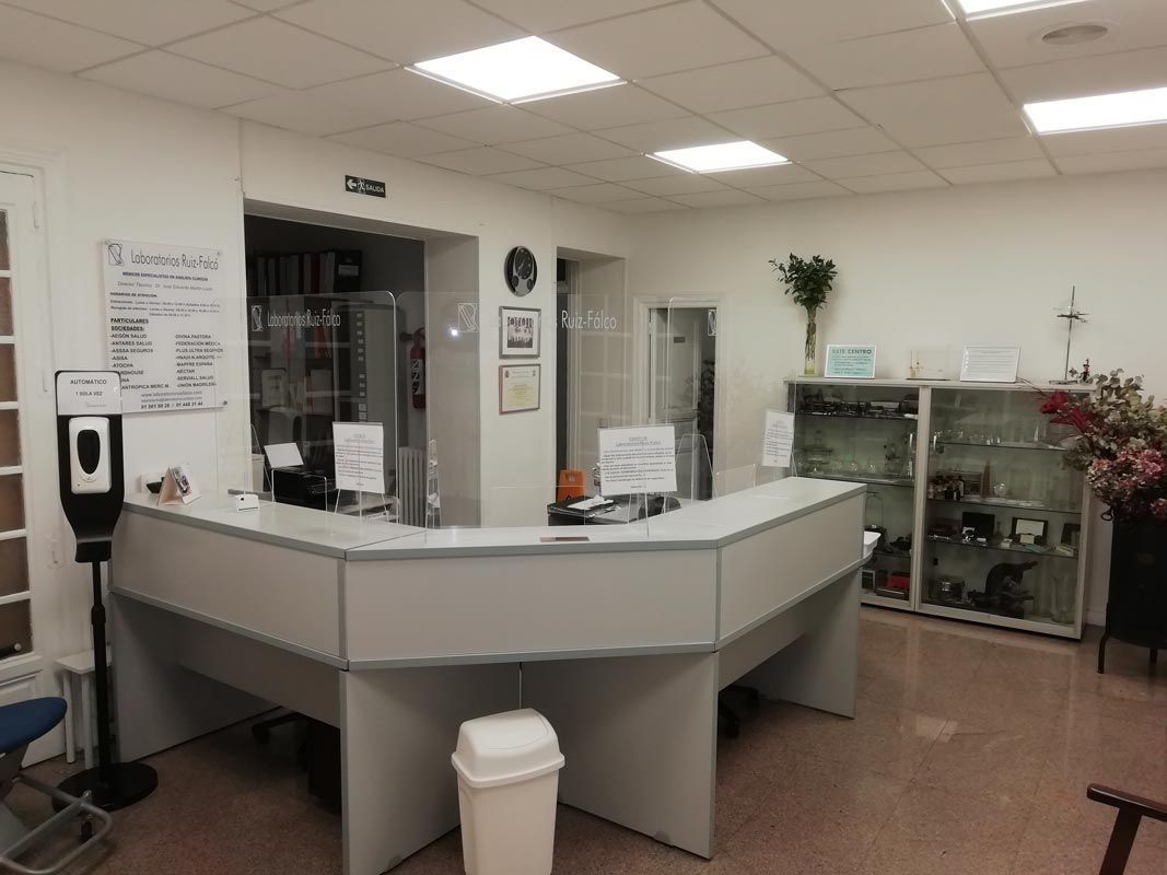 Un área de recepción en un hospital con un escritorio y un bote de basura.